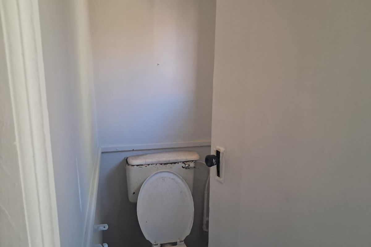 A small, dated bathroom featuring a standard toilet and cistern, requiring cosmetic updates and maintenance to improve its overall condition.