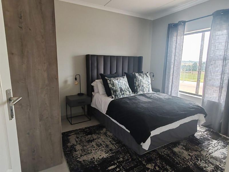 A modern bedroom featuring tiled flooring, a built-in wardrobe, and a large window providing natural light.