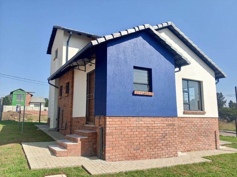 A modern residential house exterior featuring a combination of face brick and painted plaster finishes with a tiled roof and paved entrance area.