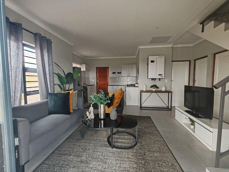 Modern open-plan living area featuring a functional kitchen with built-in cabinetry, tiled flooring, and an integrated inverter system.
