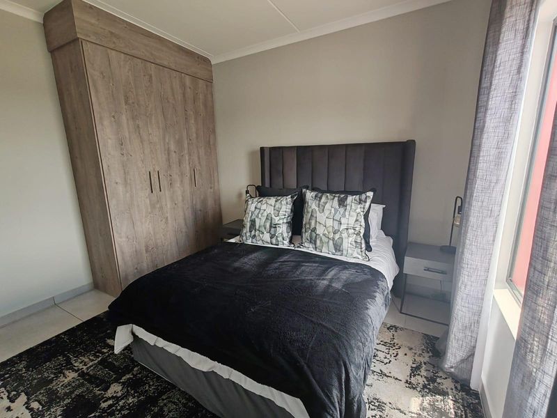 A well-maintained bedroom featuring neutral walls, tiled flooring, and a large built-in wardrobe providing ample storage space.
