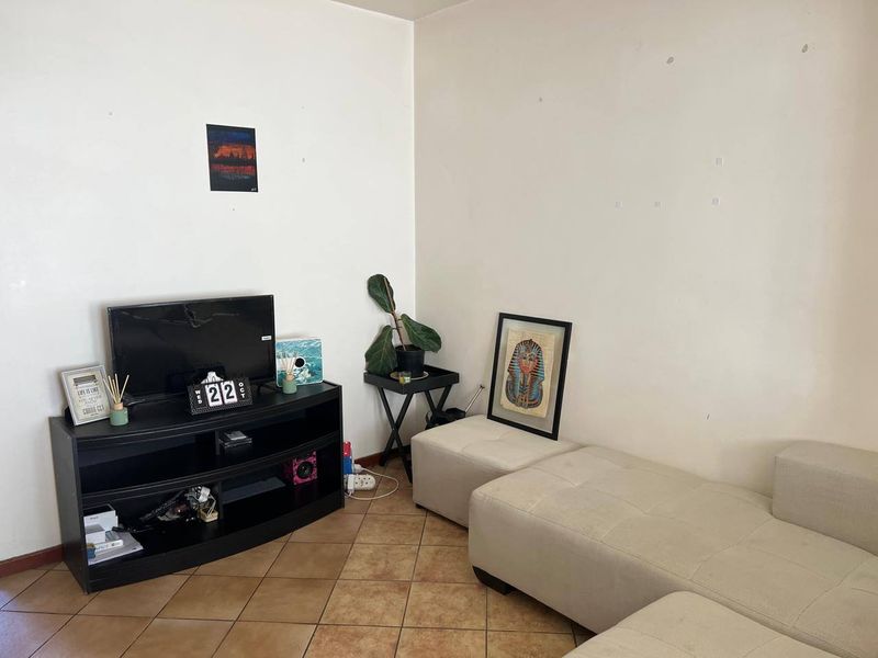A living room area featuring tiled flooring and plain walls, providing a functional space ready for personalization.