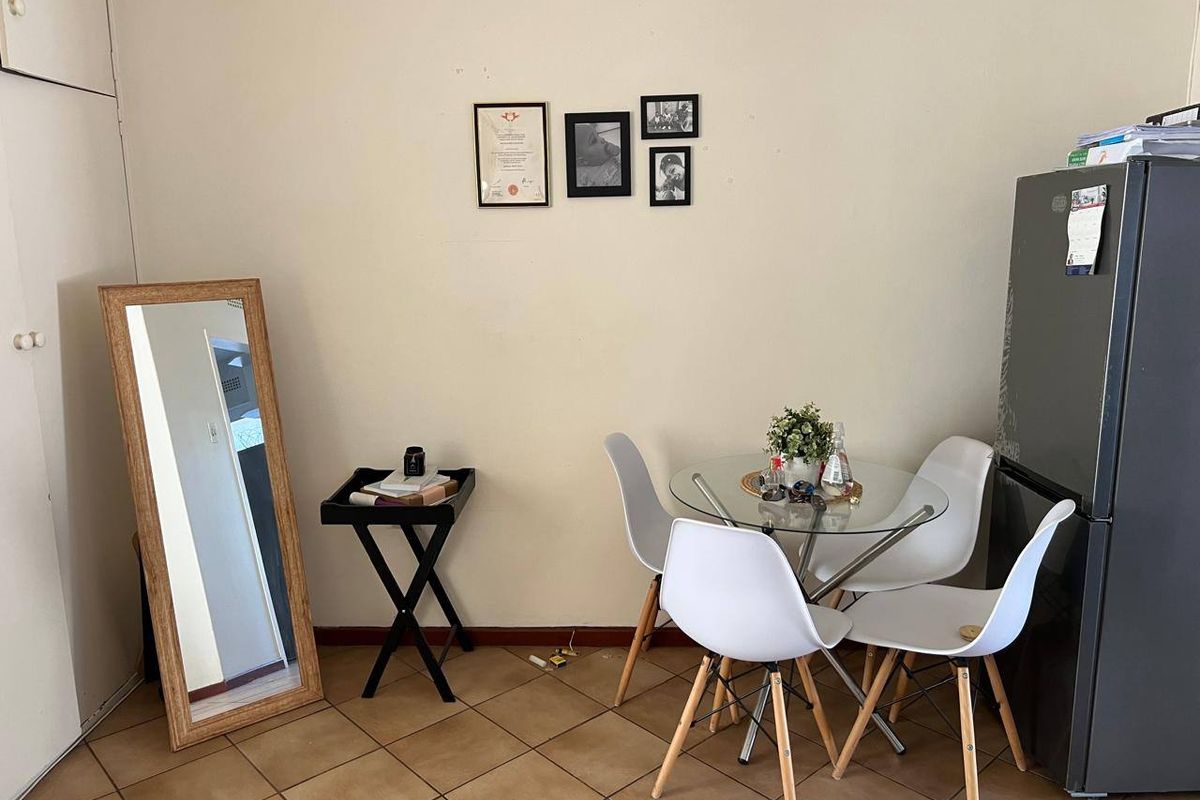 A functional dining area featuring tiled flooring and a built-in storage cupboard, providing a practical space for meals.