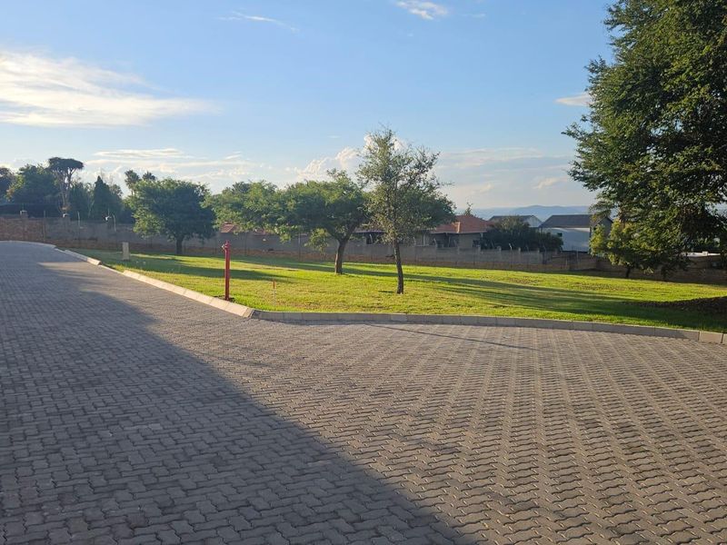 A view of the property's paved driveway and adjacent landscaped lawn area, enclosed by a perimeter wall.