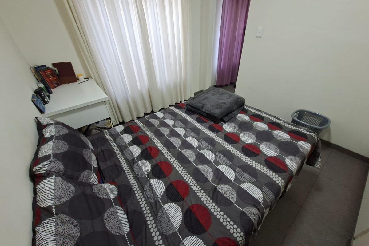 A functional bedroom featuring tiled flooring and window treatments, offering a neutral base ready for personalization.