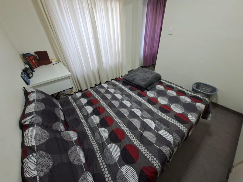 A functional bedroom featuring tiled flooring and window treatments, offering a neutral base ready for personalization.