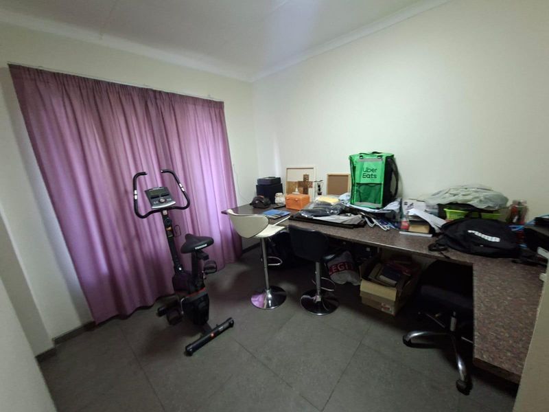 A functional office space featuring a built-in desk and tiled flooring, suitable for a home workspace or study area.