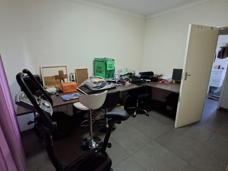 A functional office space featuring tiled flooring and a built-in desk, offering a versatile area for work or study.