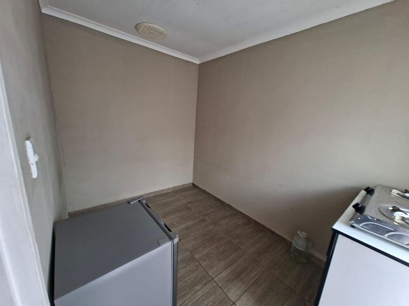 A compact, empty kitchen area featuring tiled flooring and neutral wall finishes, providing a blank canvas for potential renovation or layout customization.