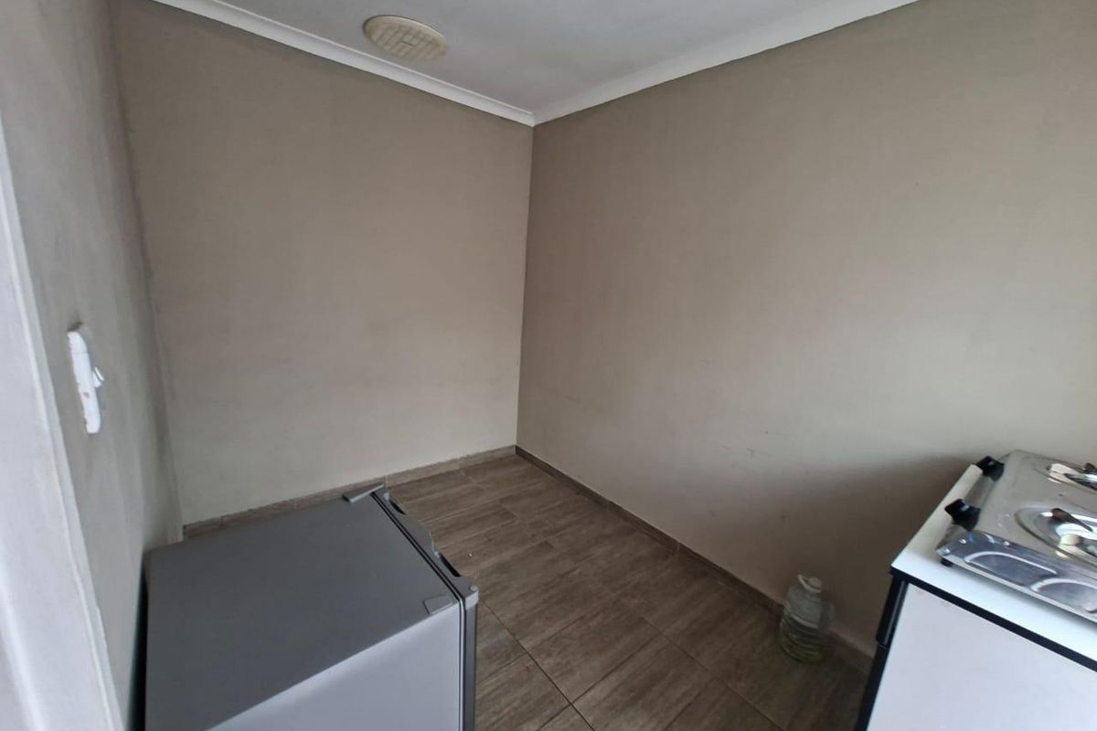 A compact, empty kitchen area featuring tiled flooring and neutral wall finishes, providing a blank canvas for potential renovation or layout customization.