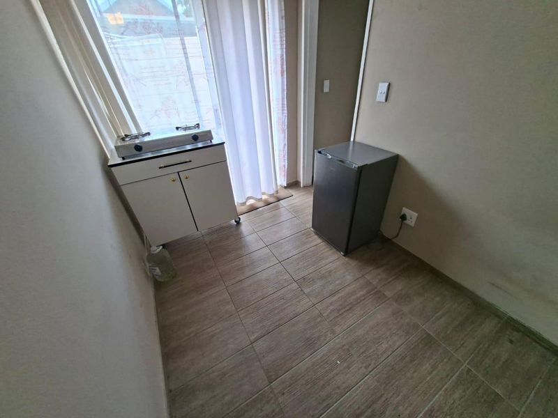 A compact kitchen area featuring tiled flooring and a sliding door leading to the exterior, providing a functional space for basic meal preparation.