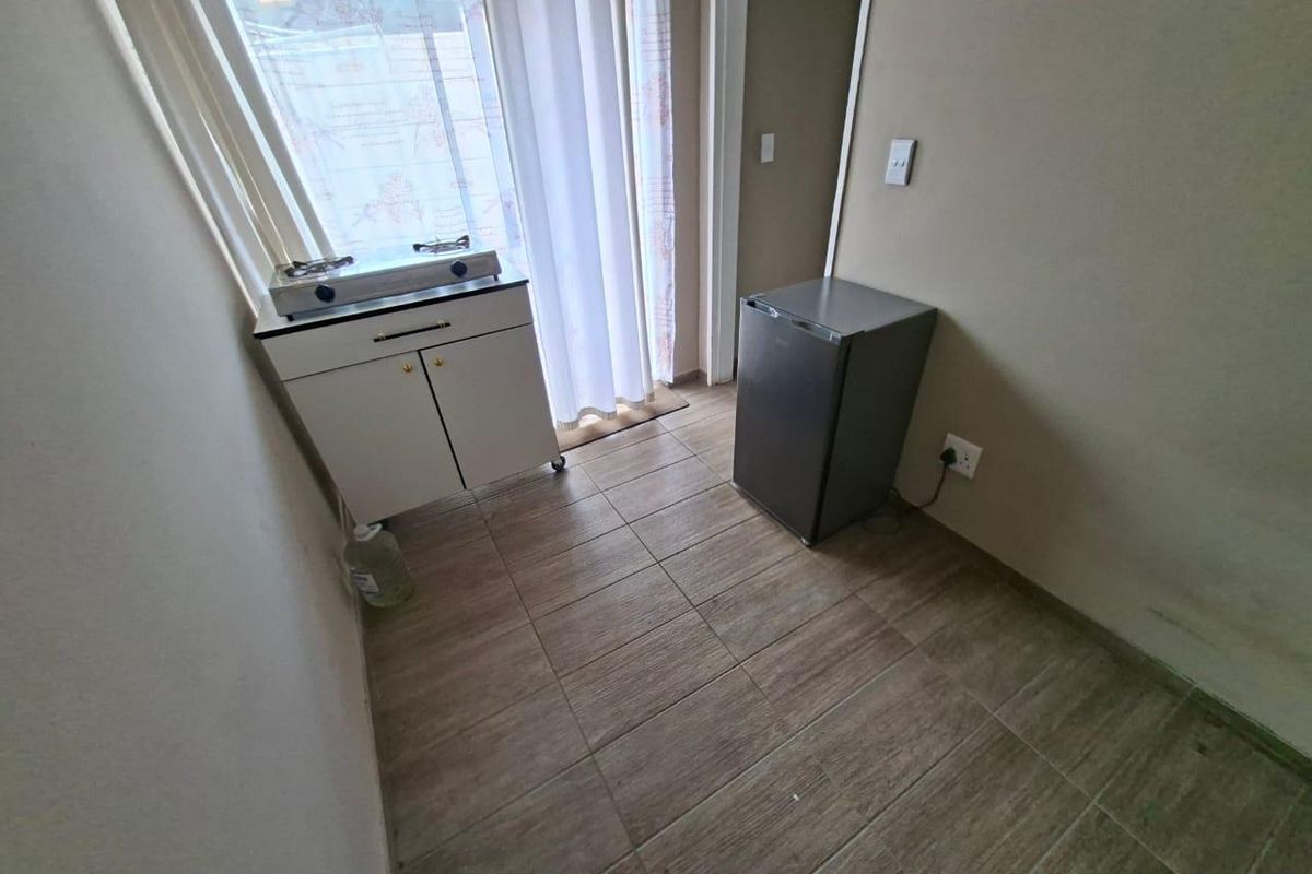 A compact kitchen area featuring tiled flooring and a sliding door leading to the exterior, providing a functional space for basic meal preparation.