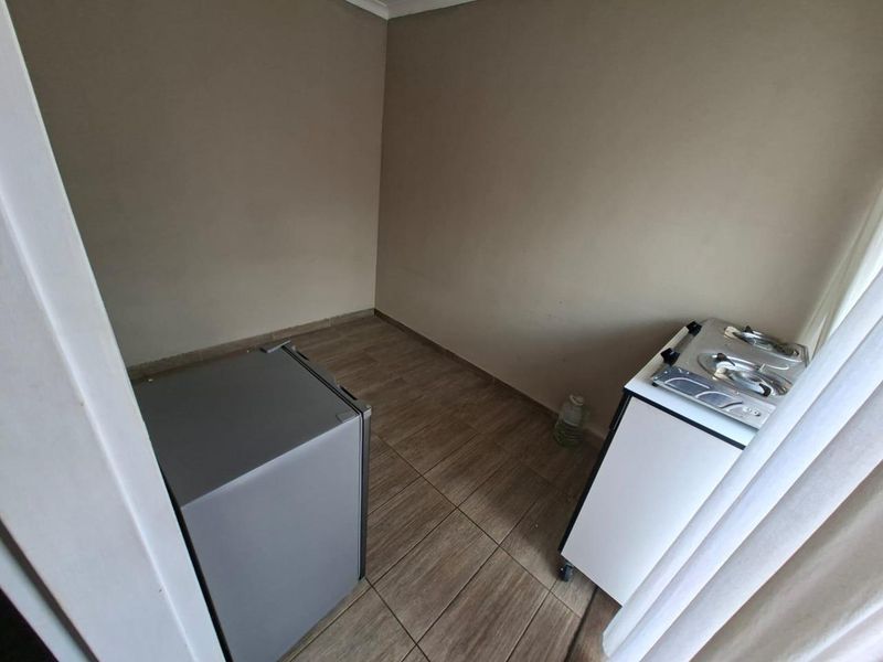 A compact kitchen area featuring tiled flooring and a portable gas cooktop, offering a functional space for basic meal preparation.