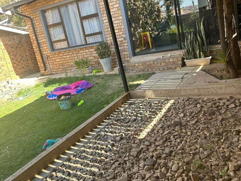 Covered patio area featuring a corrugated metal roof, brick exterior walls, and direct access to the garden through sliding glass doors.
