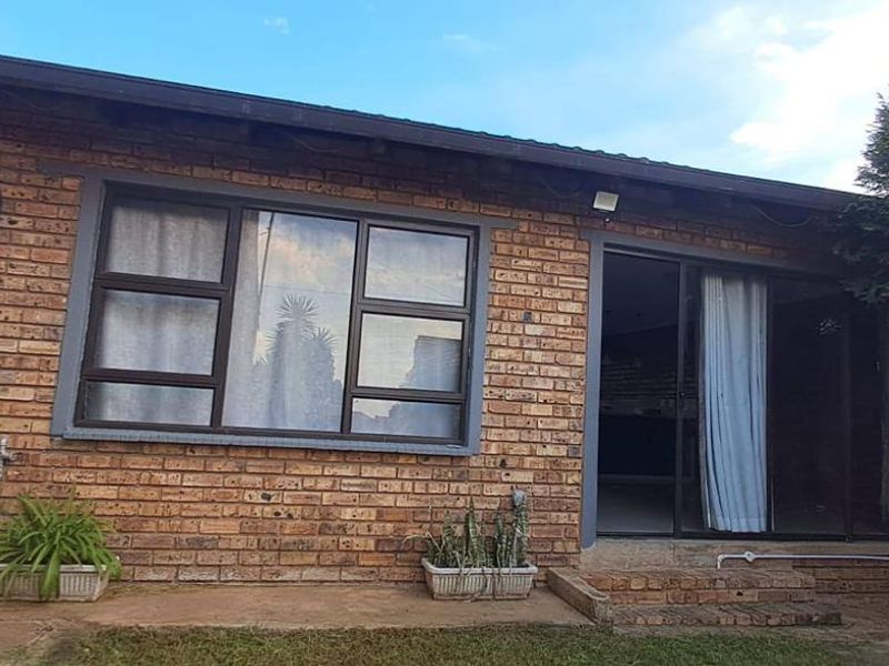 Rear exterior view of a face brick house featuring a sliding glass door and aluminium window frames.