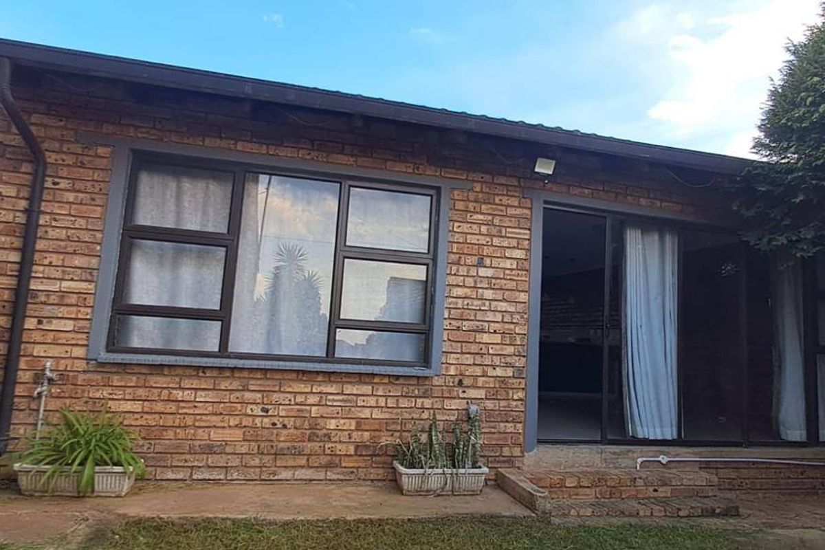 Rear exterior view of a face brick house featuring a sliding glass door and aluminium window frames.