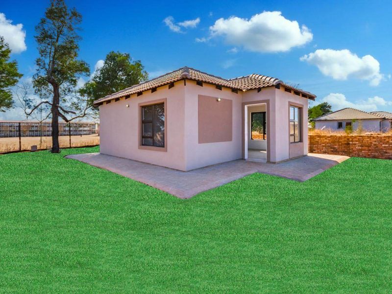 Rear view of a detached house featuring a paved patio area and a tiled roof, set against a landscaped lawn.