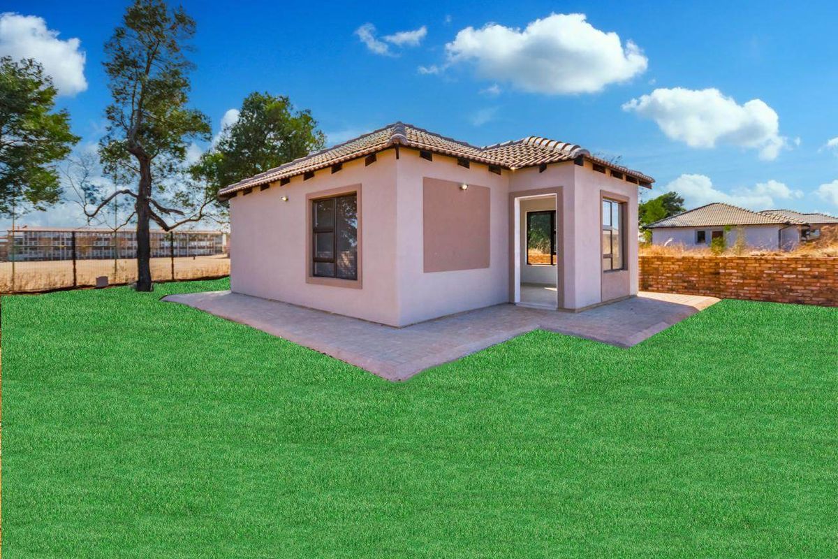 Rear view of a detached house featuring a paved patio area and a tiled roof, set against a landscaped lawn.