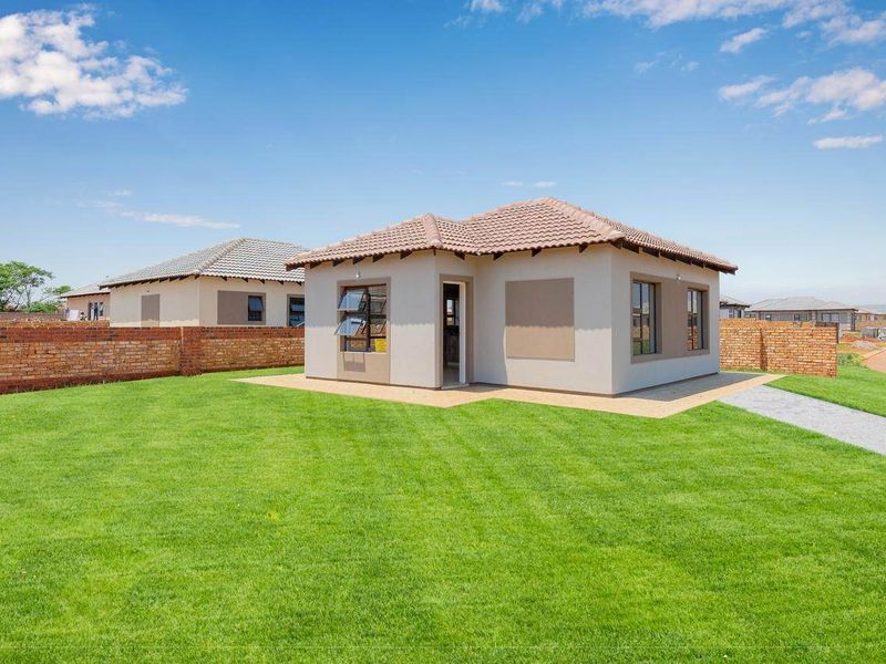 A well-maintained detached house featuring a tiled roof, aluminium window frames, and a spacious private garden enclosed by a brick boundary wall.