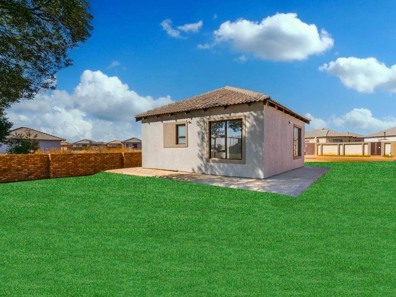 A view of the rear exterior of the house featuring a paved patio area, tiled roof, and a brick boundary wall set in a garden.