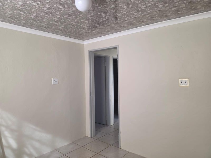 An empty bedroom featuring tiled flooring, a textured ceiling with coving, and neutral wall finishes, providing a blank canvas for interior design.
