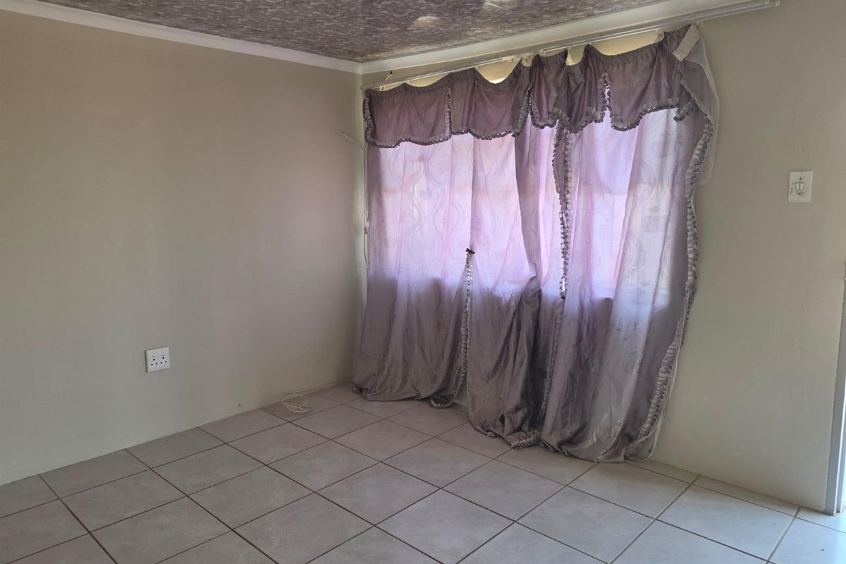 A vacant living room featuring neutral tiled flooring and a textured ceiling finish, providing a blank canvas for interior design.
