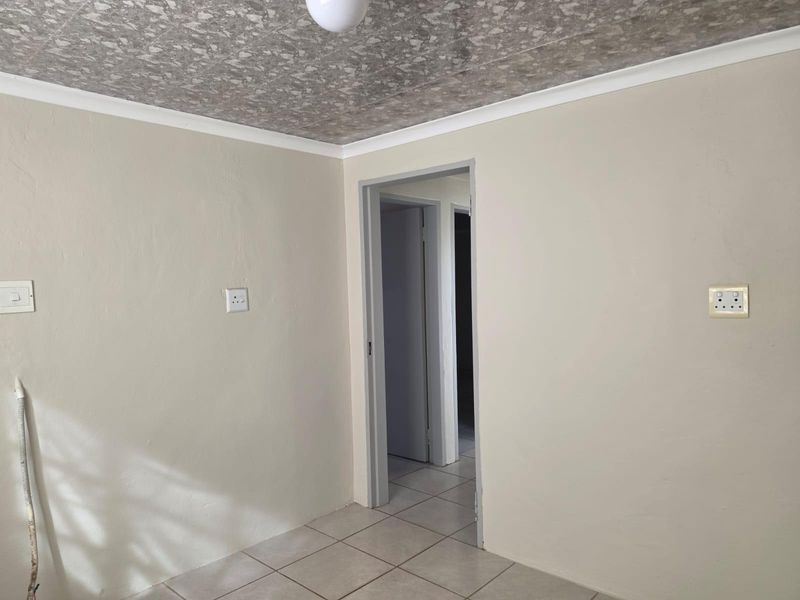An empty bedroom featuring neutral wall paint, tiled flooring, and a textured ceiling finish, providing a blank canvas for interior design.