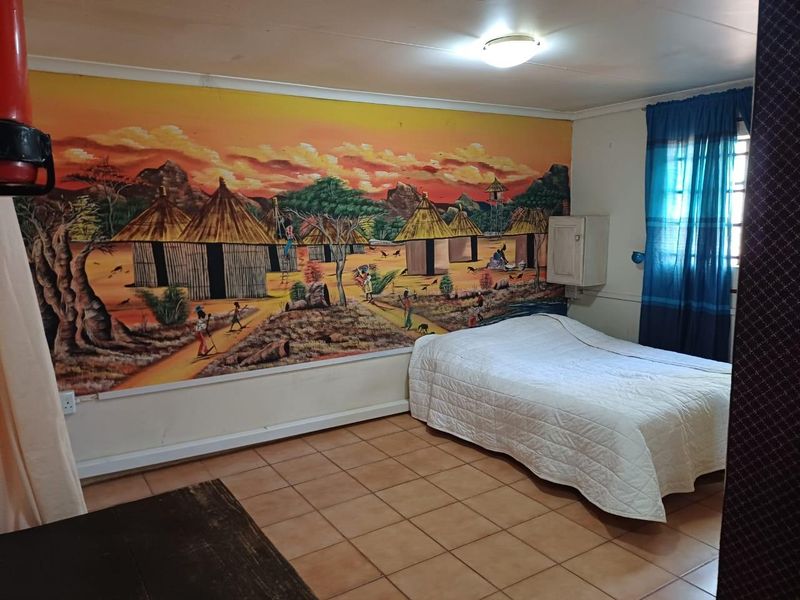A bedroom featuring tiled flooring and a large decorative wall mural, providing a unique aesthetic that could be updated with modern finishes.