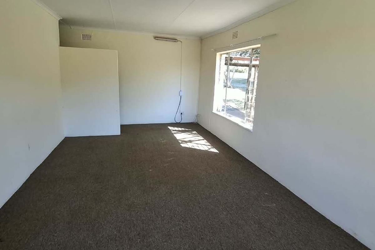 An empty living room featuring carpet flooring and a window, providing a blank canvas for potential renovation and interior design updates.