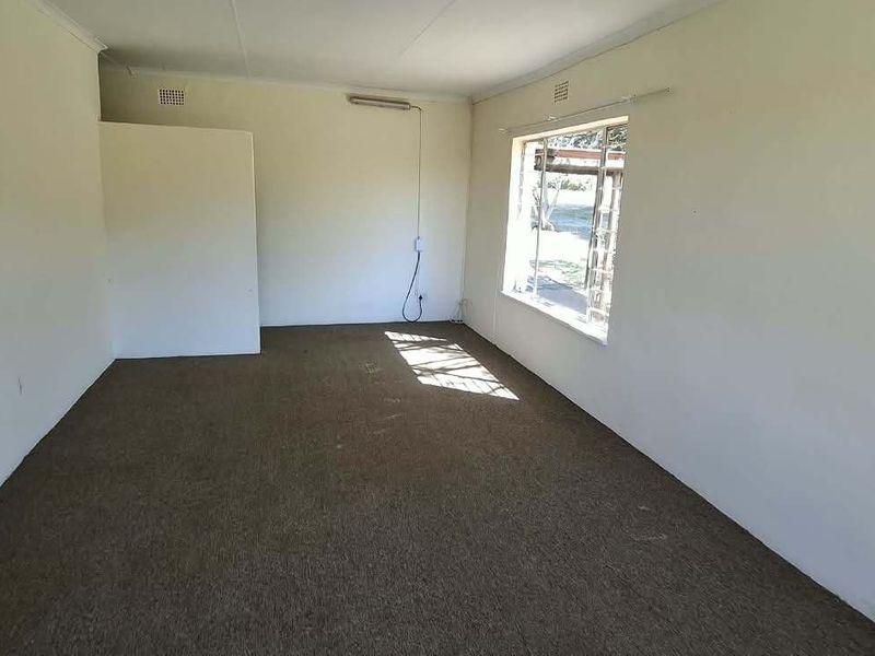 An empty living room featuring carpet flooring and a window, providing a blank canvas for potential renovation and interior design updates.