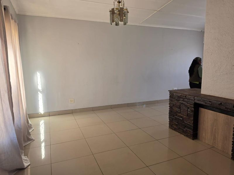 An empty living room featuring neutral tiled flooring and a decorative stone-clad feature wall, offering a clean and versatile space.