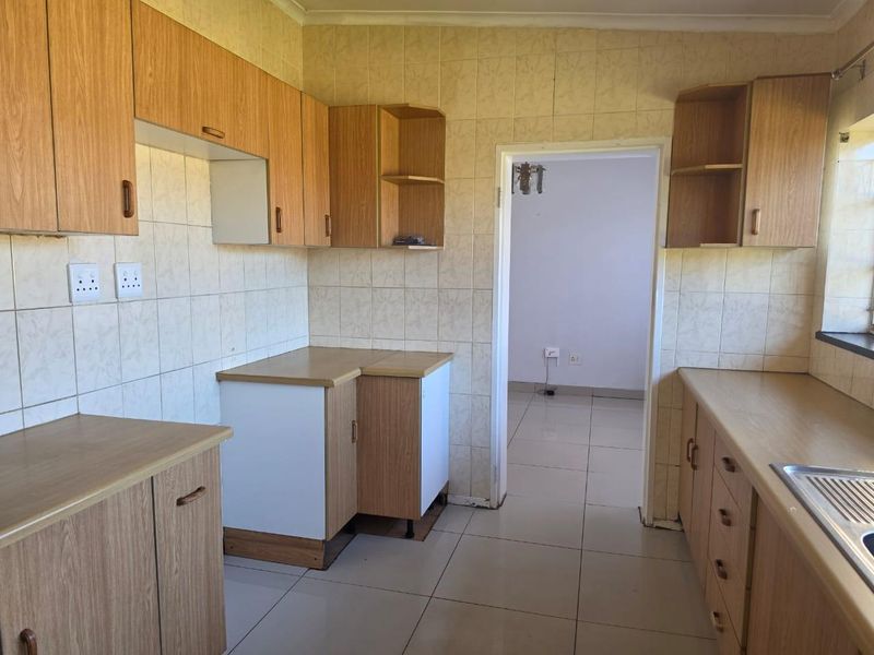A functional kitchen featuring laminate cabinetry, tiled walls, and tiled flooring, offering a clean and neutral space ready for modern updates.