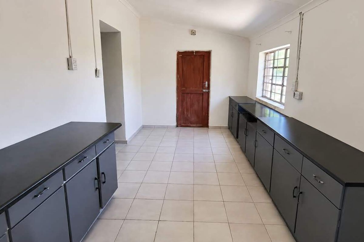 A functional, empty kitchen space featuring extensive built-in cabinetry, dark countertops, and tiled flooring, ready for modernization or customization.