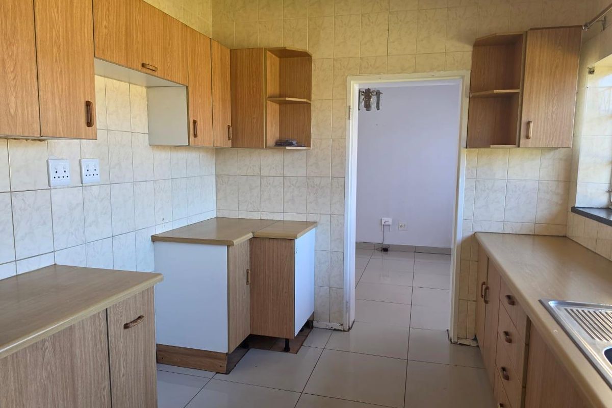 A functional kitchen featuring laminate cabinetry, tiled walls, and tiled flooring, offering a clean and neutral space ready for modern updates.
