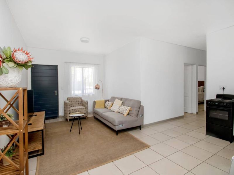 An open-plan living area featuring tiled flooring, a compact kitchen corner with a built-in oven, and direct access to adjacent rooms.