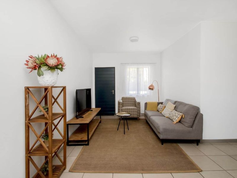 A bright and neutral living room featuring tiled flooring and a simple, clean layout suitable for various interior design styles.