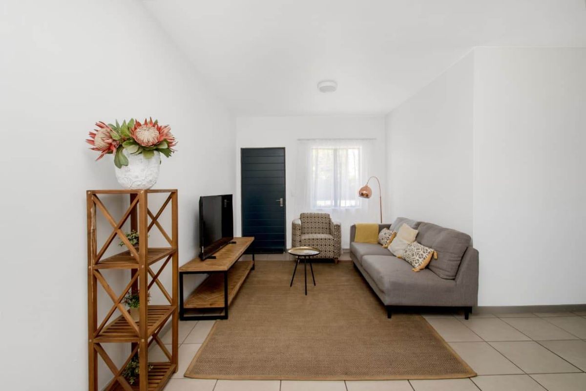 A bright and neutral living room featuring tiled flooring and a simple, clean layout suitable for various interior design styles.