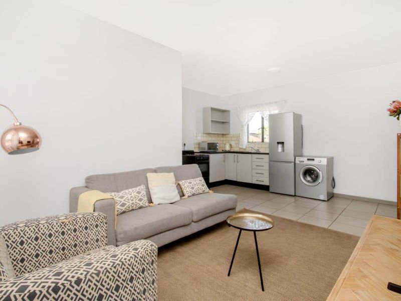 Open-plan living area featuring a functional kitchen with built-in cabinetry, tiled flooring, and a neutral color palette throughout the space.