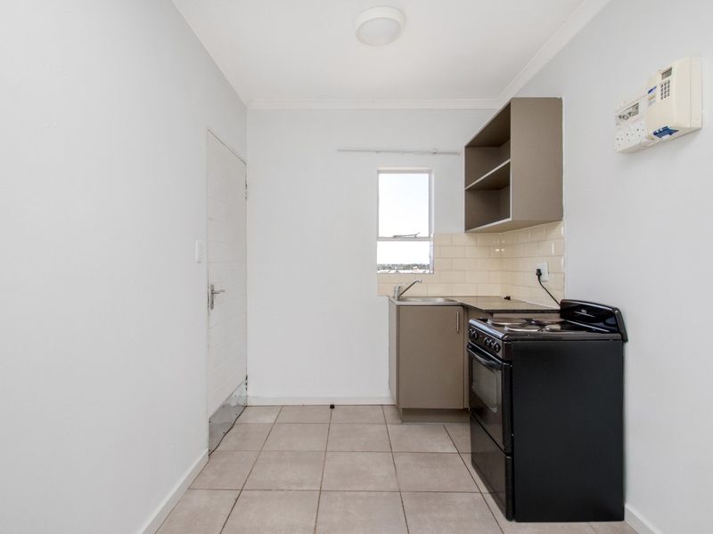 A compact, functional kitchen featuring tiled flooring, a tiled backsplash, built-in cabinetry, and a freestanding stove.