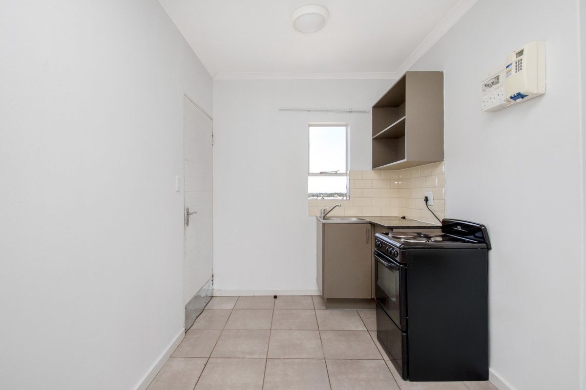 A compact, functional kitchen featuring tiled flooring, a tiled backsplash, built-in cabinetry, and a freestanding stove.
