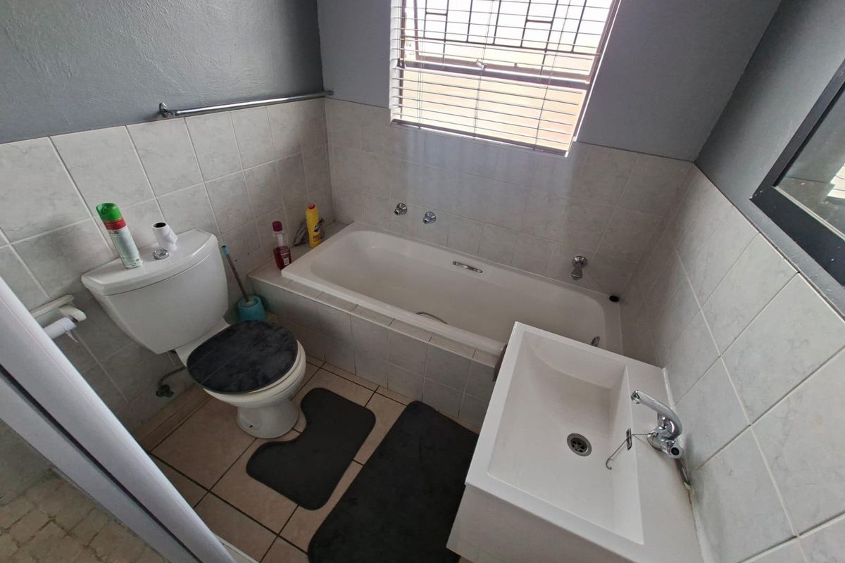 A functional bathroom featuring a bathtub, wall-mounted basin, and toilet with tiled splashbacks and neutral finishes.