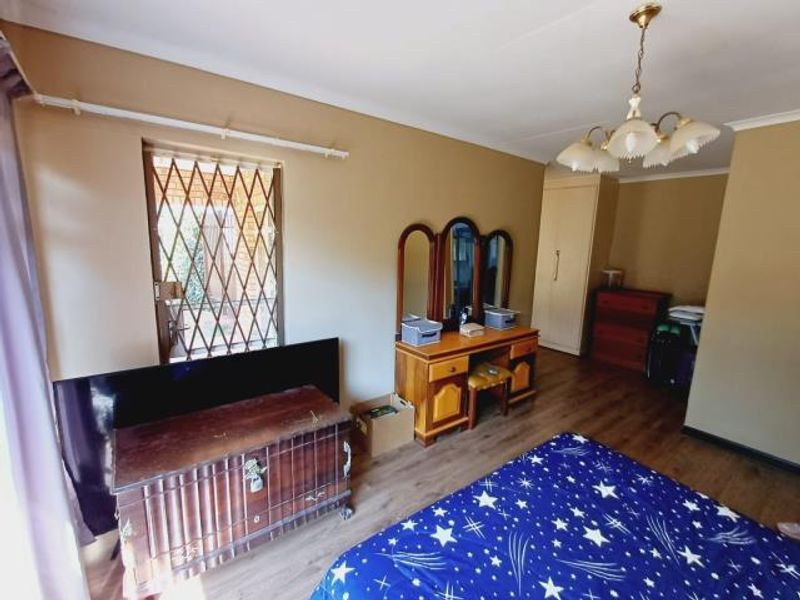 A bedroom featuring laminate flooring, a built-in wardrobe, and a security gate on the window.