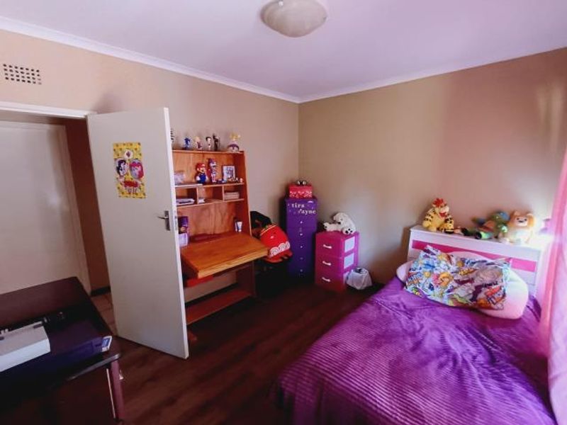 A standard bedroom featuring laminate flooring and neutral wall tones, providing a functional space for rest or study.