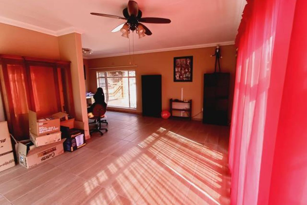 A spacious living area featuring tiled flooring and a ceiling fan, offering a versatile layout with natural light.