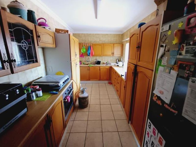 A functional galley-style kitchen featuring traditional wooden cabinetry, tiled flooring, and integrated oven, offering potential for a modern cosmetic update.