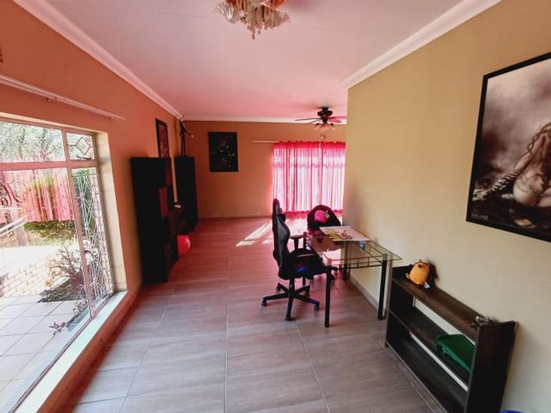 Spacious living area featuring tiled flooring, a ceiling fan, and large sliding glass doors providing access to the exterior.