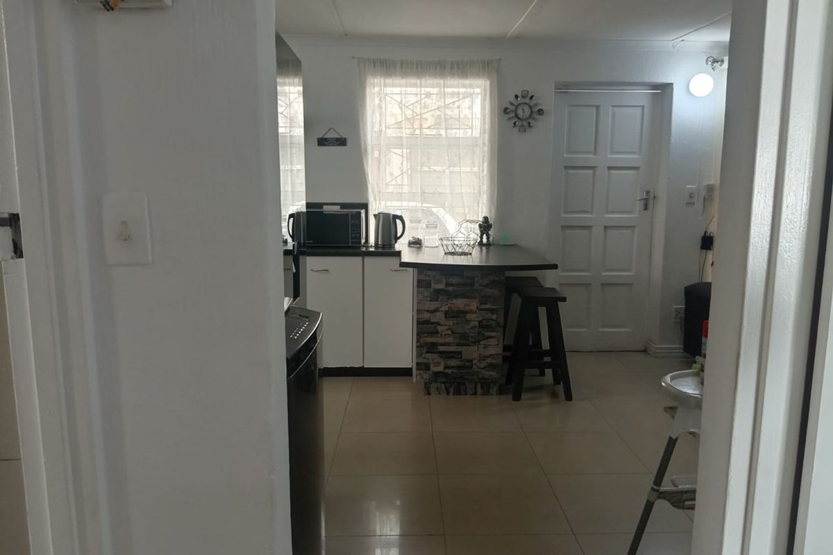 A functional kitchen area featuring tiled flooring, built-in cabinetry, a breakfast counter, and direct access to an exterior door.