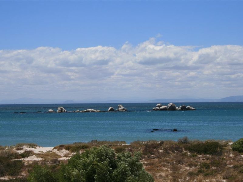 A scenic view of the ocean featuring natural rock formations and coastal vegetation, highlighting the property's prime waterfront location.