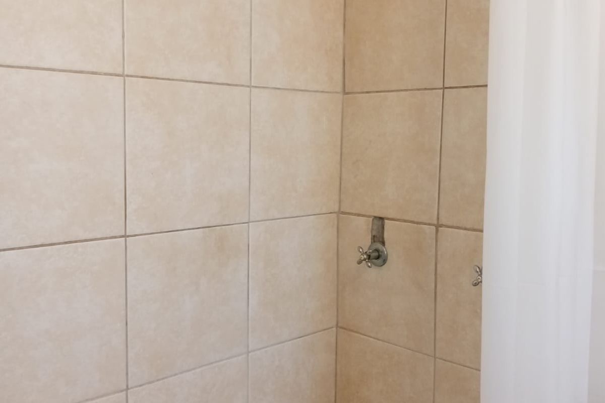 A functional bathroom shower and bathtub combination featuring neutral wall tiling and standard chrome plumbing fixtures.