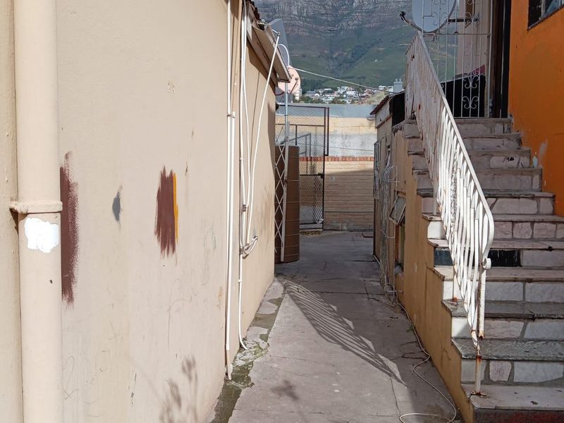 Exterior side passage featuring a concrete walkway, external staircase with metal railing, and views of the mountain in the background.